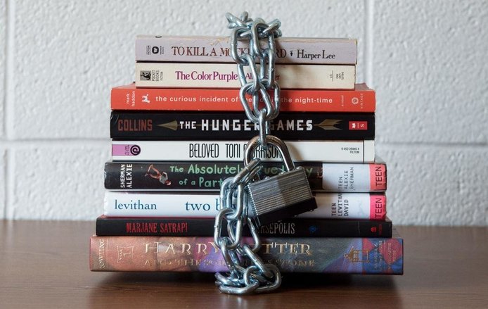 Stack of banned books with a chain locked around them sitting on a table.