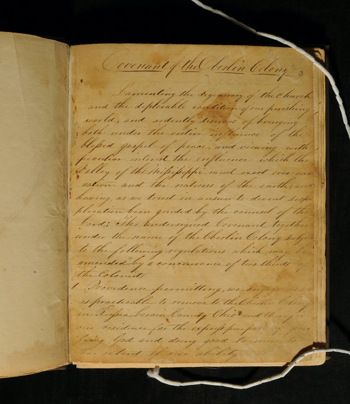 Yellow page of open book with loopy cursive written on it.