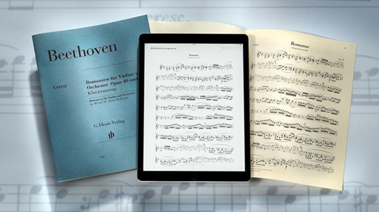 Musical scores displayed on a musical note background, two physical and one on a tablet.