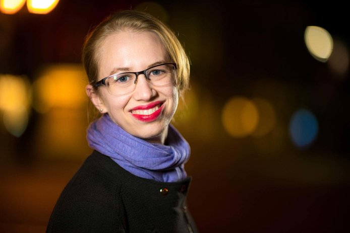 Portrait of Assistant Professor Jillian Scudder on black and yellow blurry background.