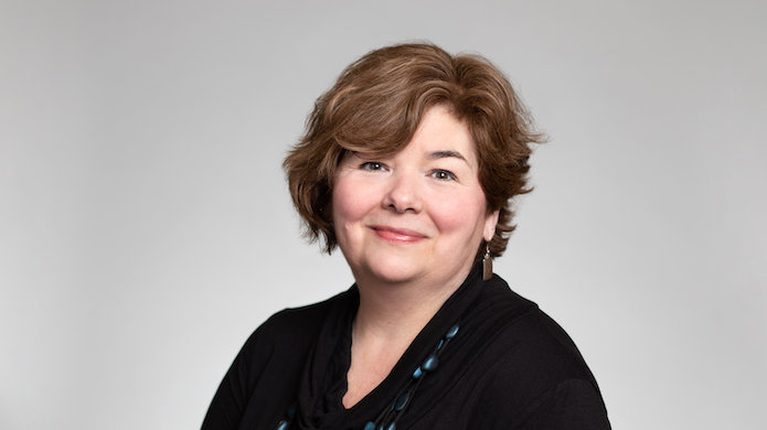 Kathy Abromeit portrait in front of gray background.
