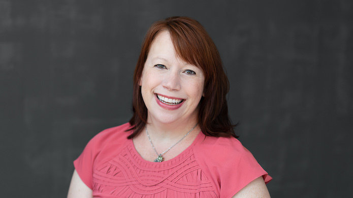 Marla Thompson portrait in front of dark gray background.