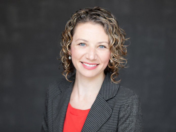 Megan Kaes Long portrait in front of dark gray background.