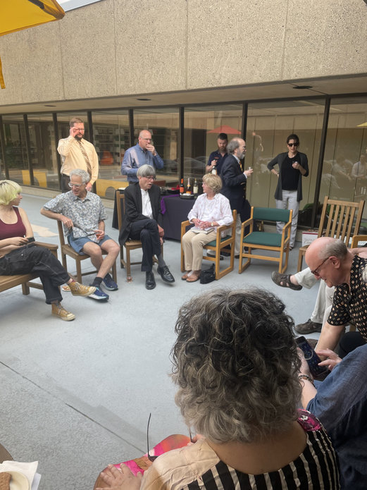 Faculty and staff seated and standing in a circle on the sundeck, talking.