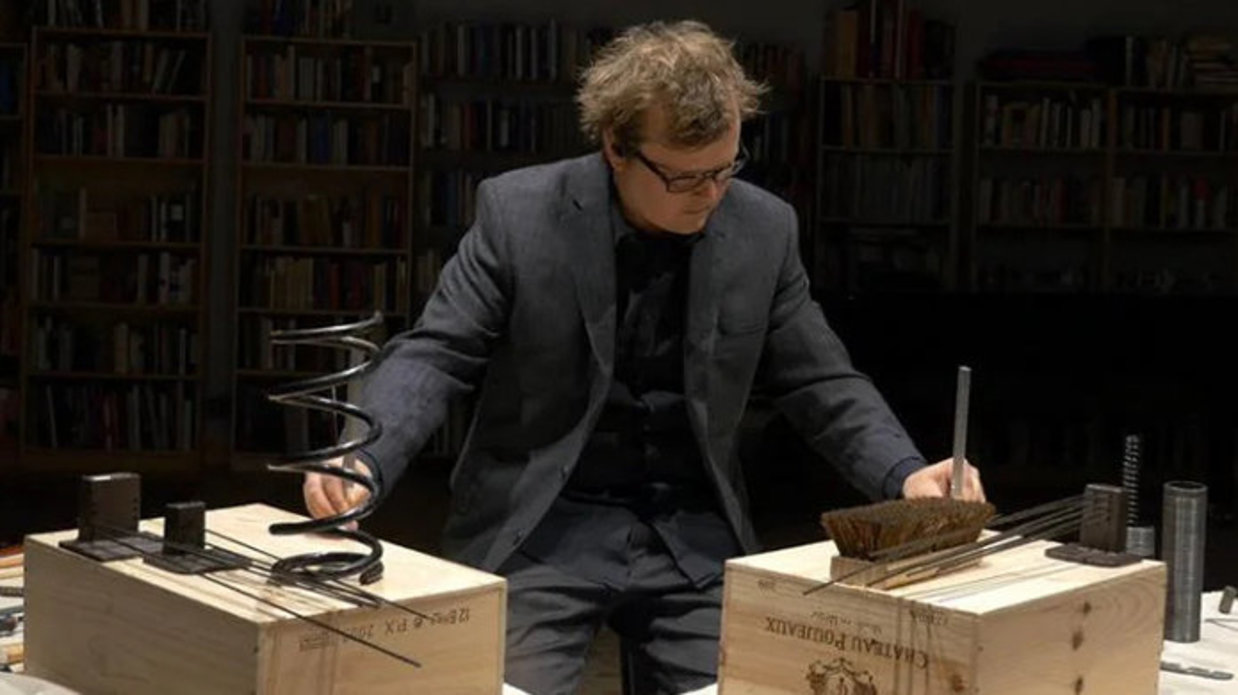 Professor Ross Karre stationed between and interacting with two displays set up on wooden boxes.