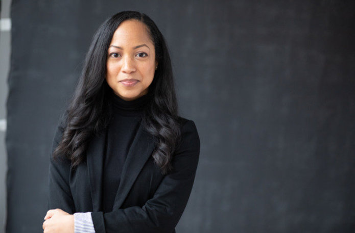 Tamika Nunley portrait, dressed in black with a dark gray background.